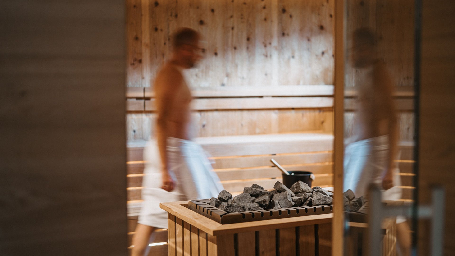 Il Lahnerhof: il vostro hotel vicino a Vipiteno centro Uomo con asciugamano nella sauna vicino al riscaldatore con pietre