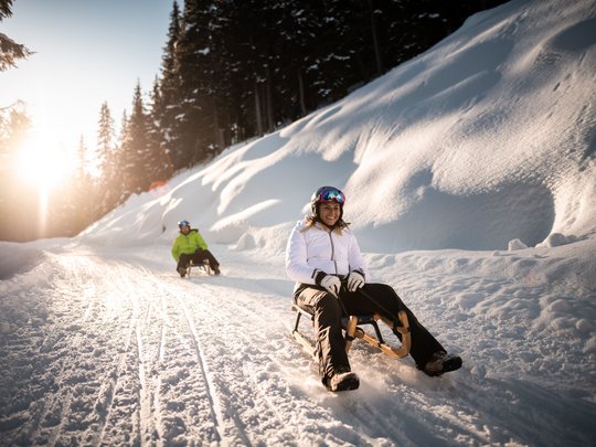 Il Lahnerhof: un hotel al Monte Cavallo, Vipiteno Donna e uomo che slittano su un sentiero innevato nel bosco al tramonto