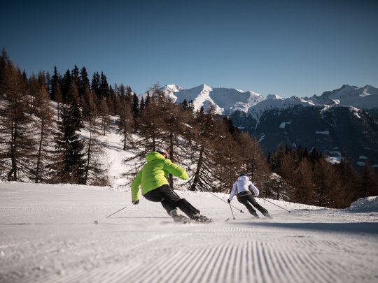 Il Lahnerhof: un hotel al Monte Cavallo, Vipiteno Due sciatori scendono una pista innevata con montagne e alberi sullo sfondo