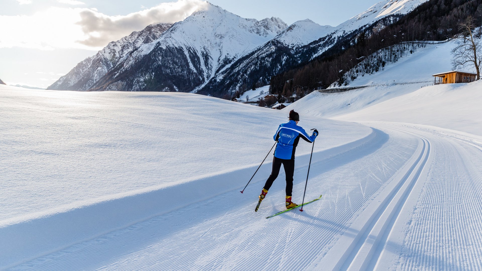 Il Lahnerhof: un hotel al Monte Cavallo, Vipiteno Sciatore di fondo con giacca blu su pista soleggiata davanti a montagne innevate