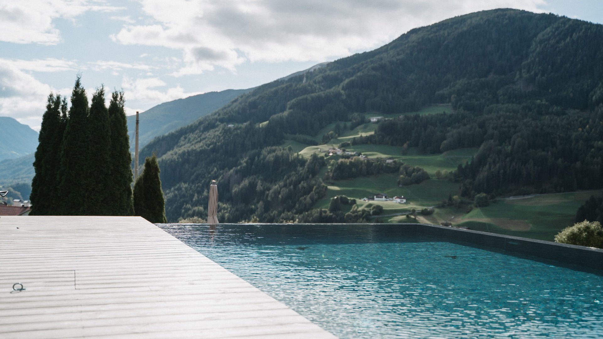 Il Lahnerhof: il vostro hotel vicino a Vipiteno centro Piscina a sfioro con vista sulle montagne e cielo nuvoloso