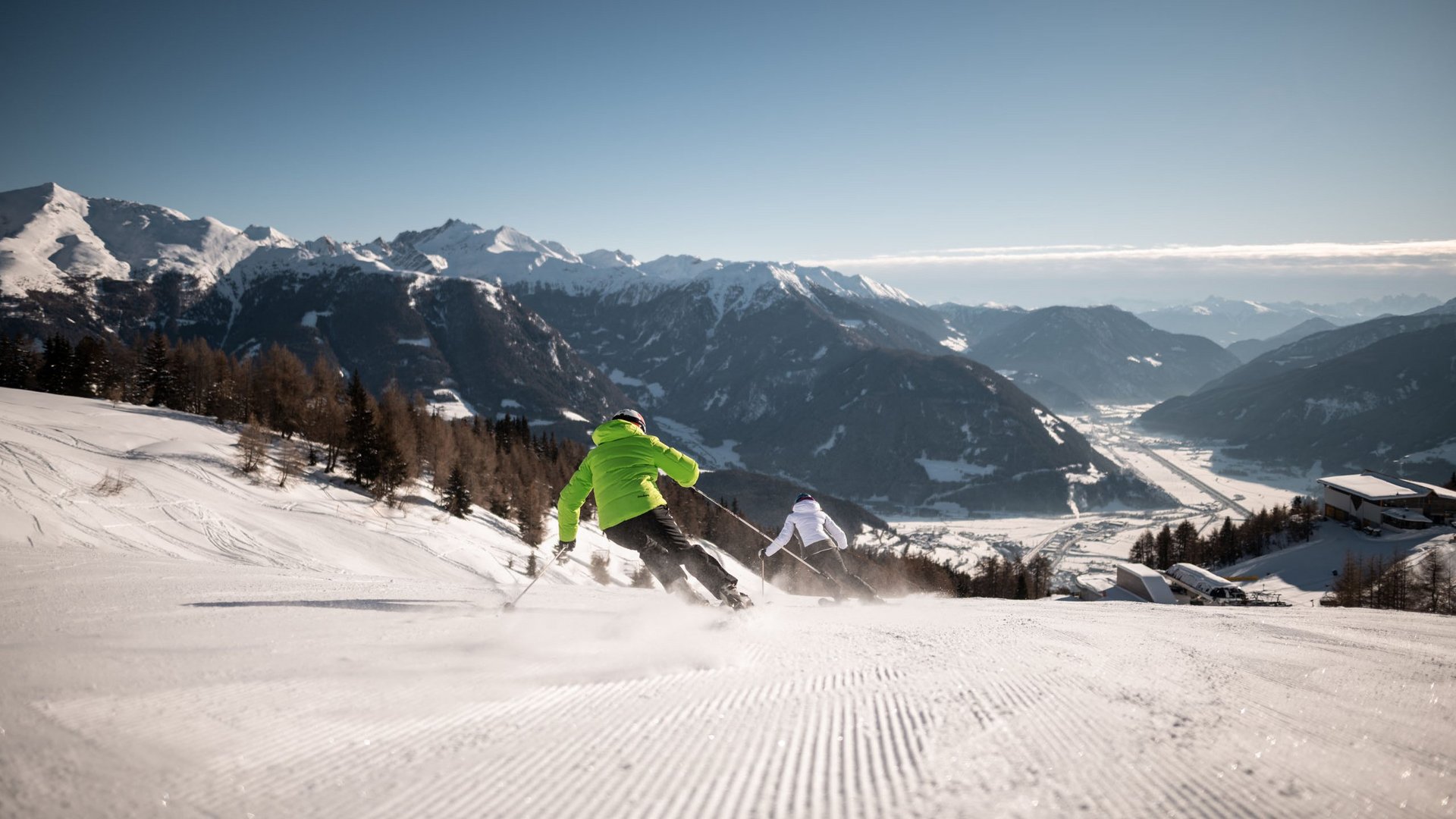 Il Lahnerhof: un hotel al Monte Cavallo, Vipiteno Due sciatori scendono una pista innevata con montagne sullo sfondo