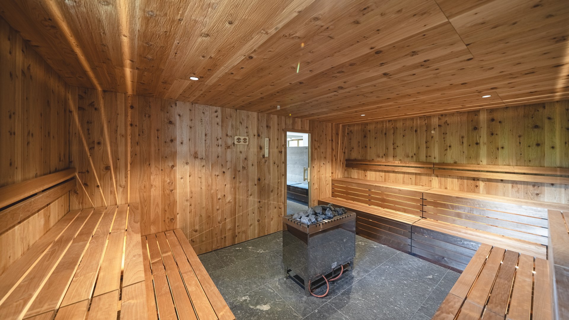 Cercate un hotel a Vipiteno con spa? Benvenuti al Lahnerhof! interno di una sauna con pareti in legno e forno centrale