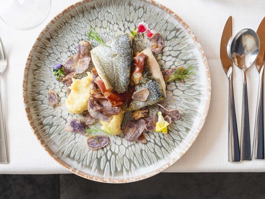 Benvenuti nel ristorante del nostro hotel con spa a Vipiteno Filetto di pesce con purè di patate e chips su piatto decorativo