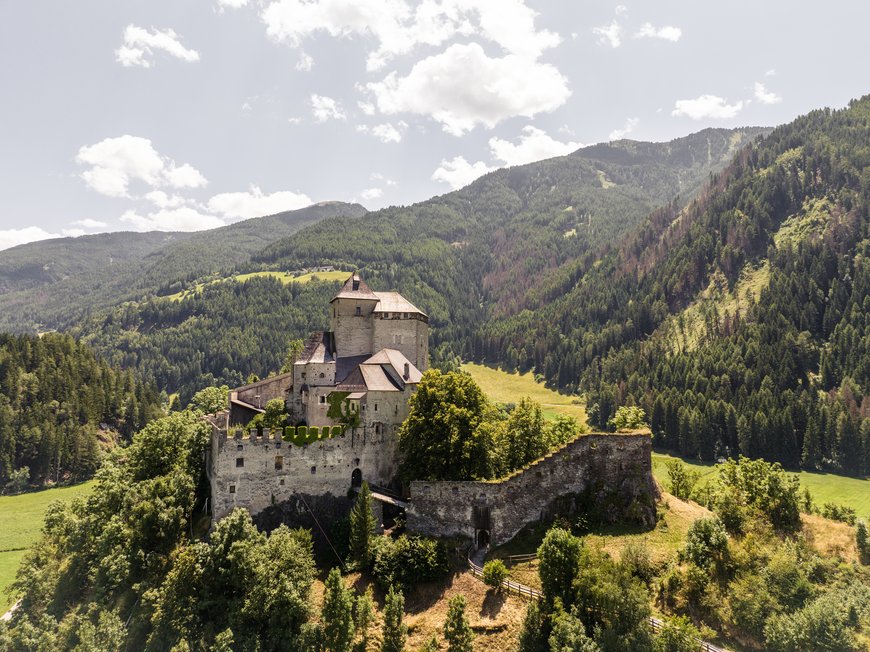 Wandern in Ratschings und Umgebung Alte Burg vor bewaldeten Bergen und blauem Himmel