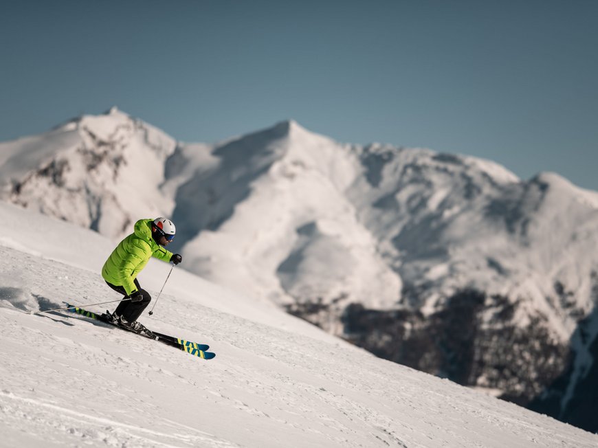 Il Lahnerhof: un hotel al Monte Cavallo, Vipiteno Scalatore con giacca verde scia su una montagna innevata con vette innevate sullo sfondo