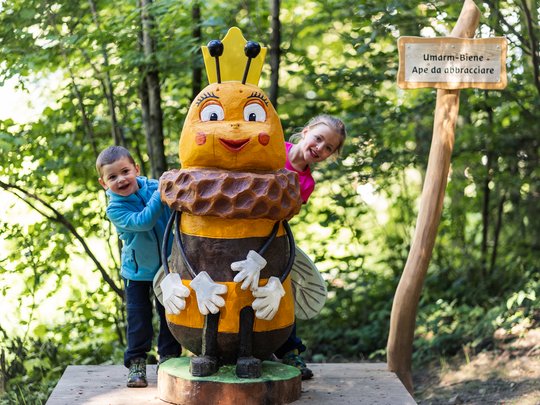 Wandern in Ratschings und Umgebung Zwei Kinder stehen neben einer großen Bienenfigur im Wald