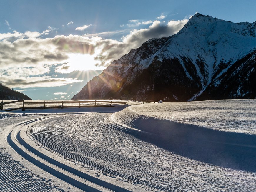Lahnerhof: Natur- und Wellnesshotel bei Sterzing Präparierte Langlaufloipe im Schnee vor schneebedeckten Bergen in der Abendsonne
