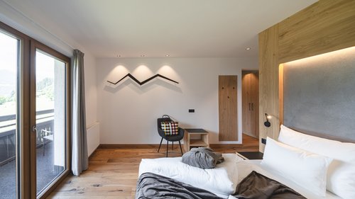 Zimmer und Suiten in unserem Hotel am Rosskopf Hell eingerichtetes Hotelzimmer mit Balkon und Holzfußboden