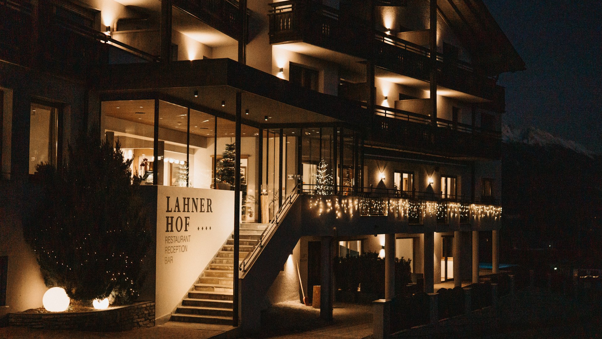 Lahnerhof: Natur- und Wellnesshotel bei Sterzing Das beleuchtete Hotel Lahner Hof bei Nacht mit Balkonen und Außentreppe