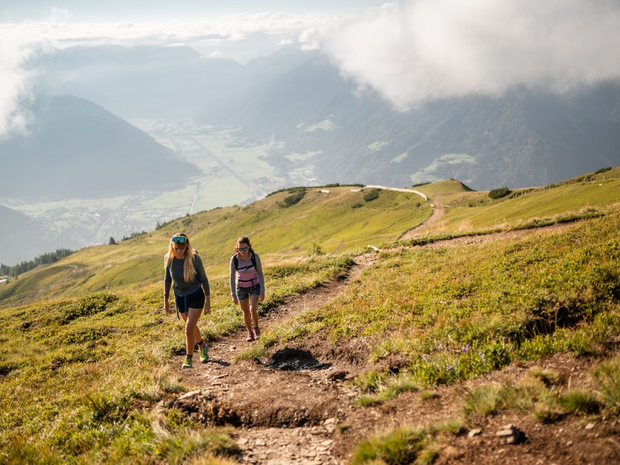 Passeggiate a Vipiteno e dintorni Due donne che camminano su un sentiero di montagna con vista sulla valle e nuvole