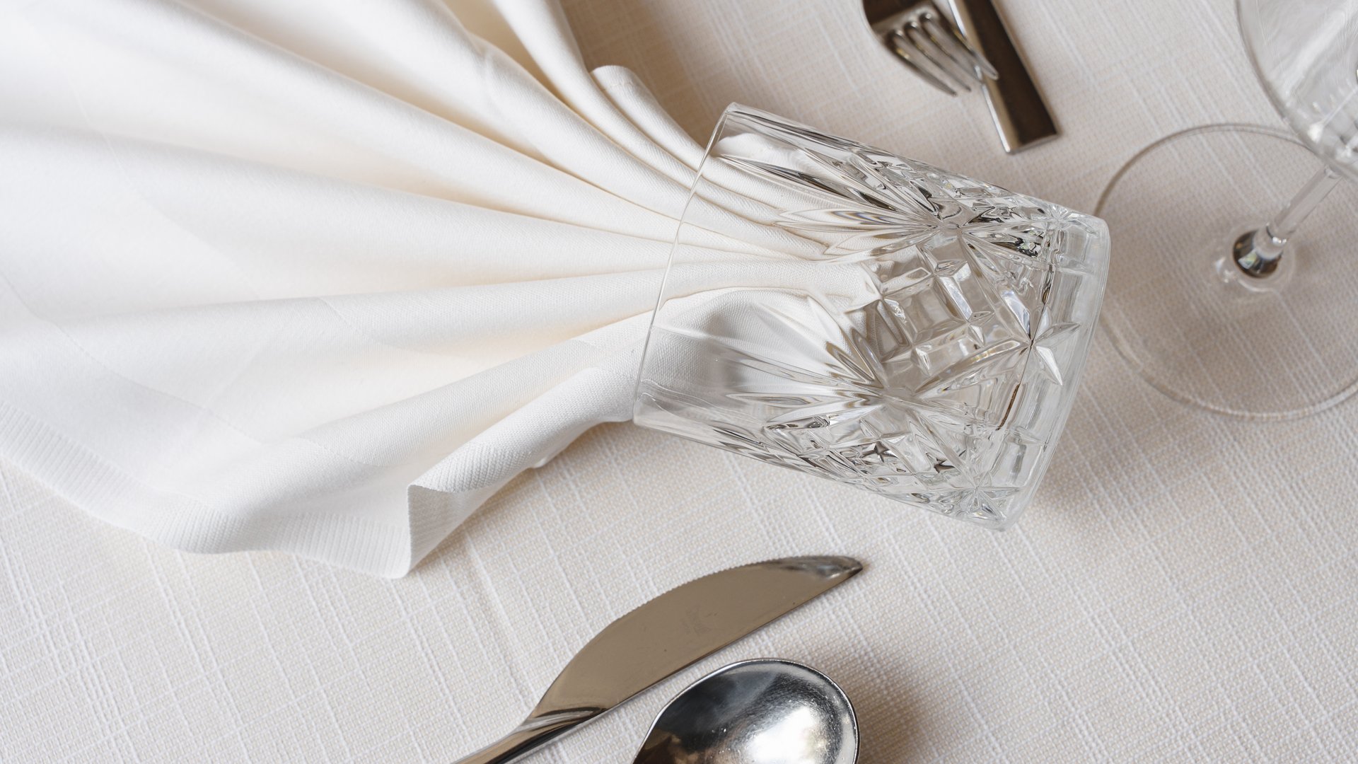 Benvenuti nel ristorante del nostro hotel con spa a Vipiteno Apparecchiatura formale con tovagliolo di stoffa piegato e bicchiere di cristallo