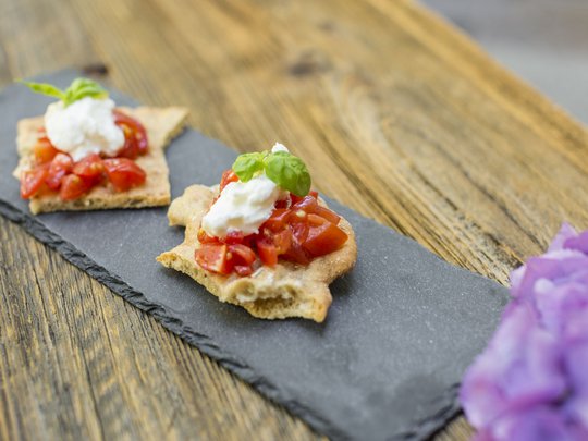 Benvenuti nel ristorante del nostro hotel con spa a Vipiteno Bruschetta con pomodori e formaggio su pietra nera su tavolo di legno