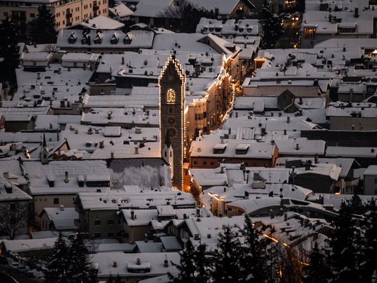 Il Lahnerhof: un hotel al Monte Cavallo, Vipiteno Villaggio innevato con torre della chiesa illuminata e case di sera