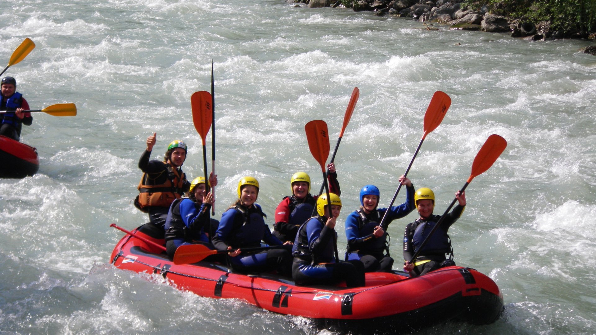 Wandern in Ratschings und Umgebung Gruppe beim Rafting auf einem wilden Fluss mit erhobenen Paddeln