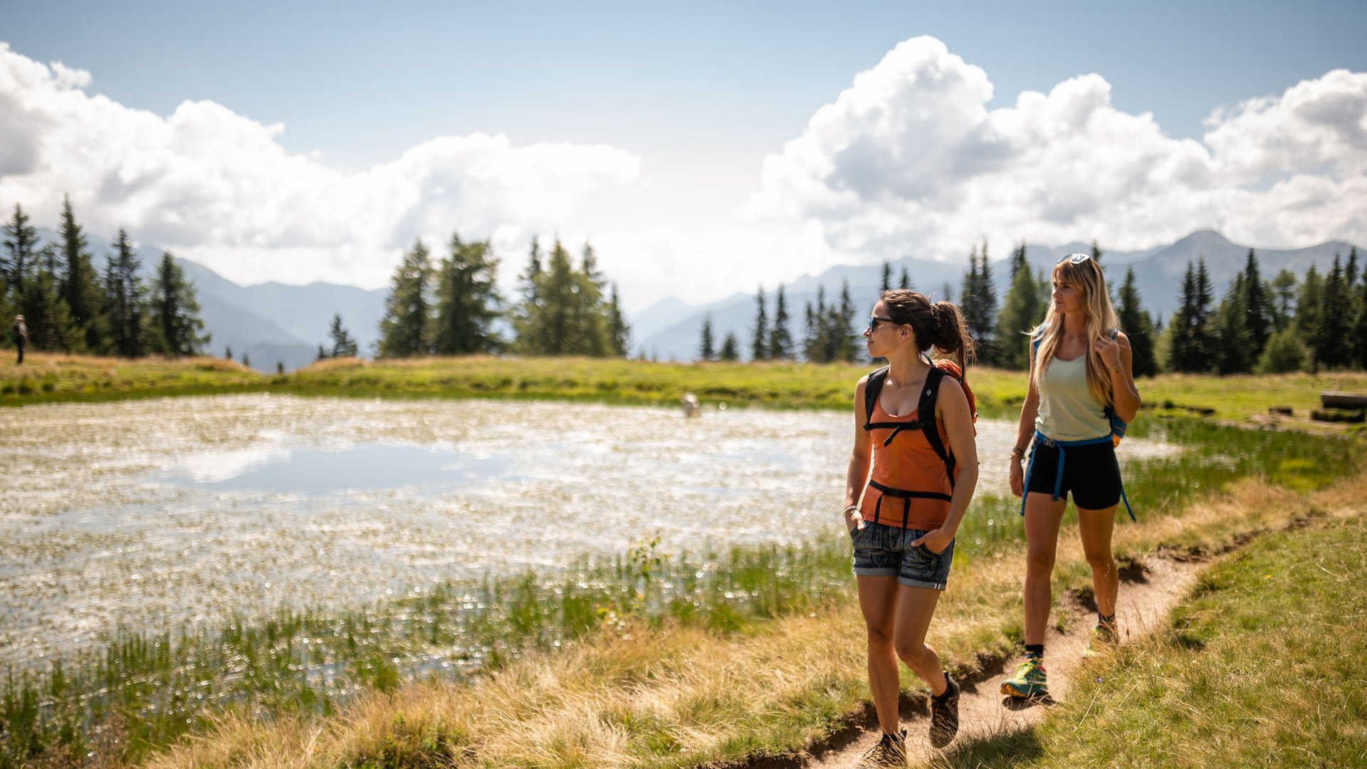 Passeggiate a Vipiteno e dintorni Due donne camminano su un sentiero accanto a un piccolo lago in montagna