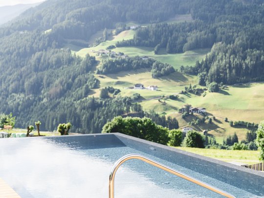 Cercate un hotel a Vipiteno con spa? Benvenuti al Lahnerhof! Piscina a sfioro con vista sulle montagne e decking in legno
