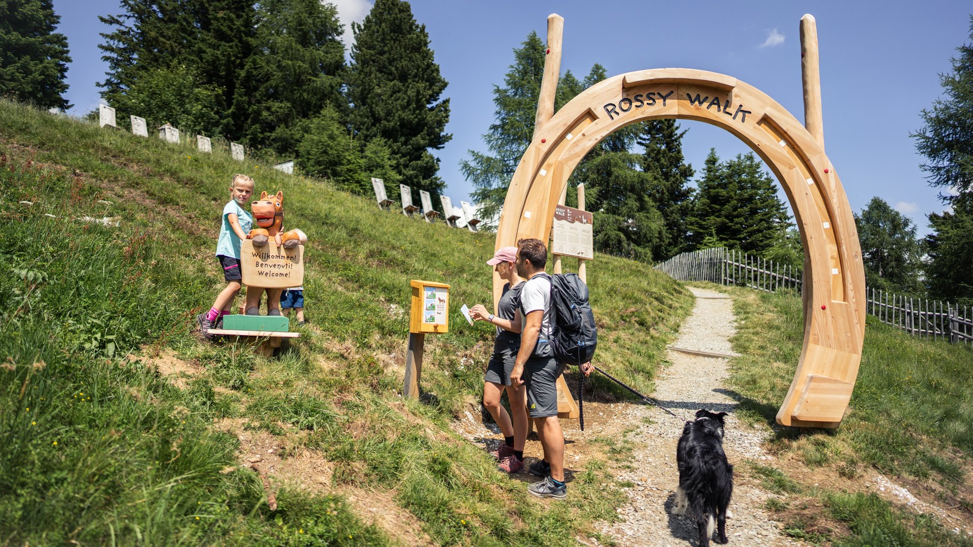 Wandern in Ratschings und Umgebung Familie mit Hund am Eingang des Rossy Walk auf einem Bergweg