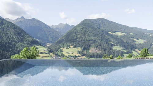 Il Lahnerhof: il vostro hotel vicino a Vipiteno centro Piscina a sfioro con vista sulle montagne verdi e valle in estate